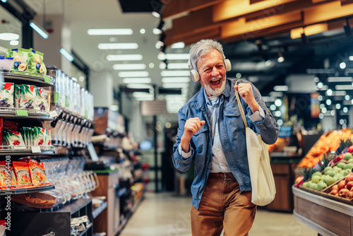 Senior man listening music at the supermarket