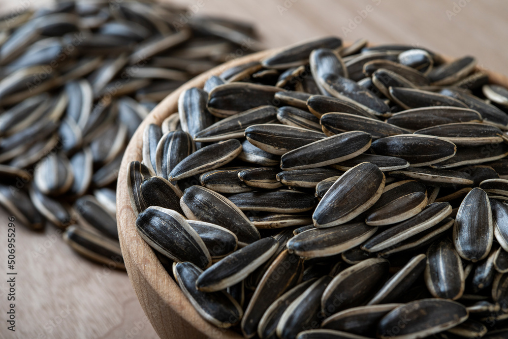 Black sunflower seeds in a bowl on wooden background