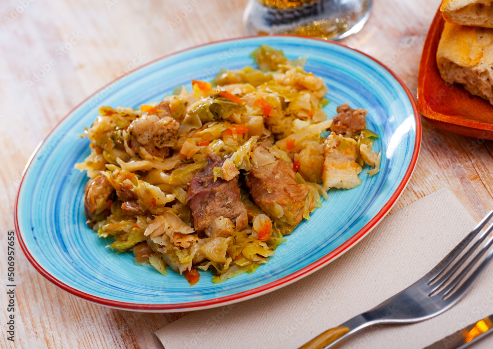Appetizing cabbage stewed with pork meat on white plate