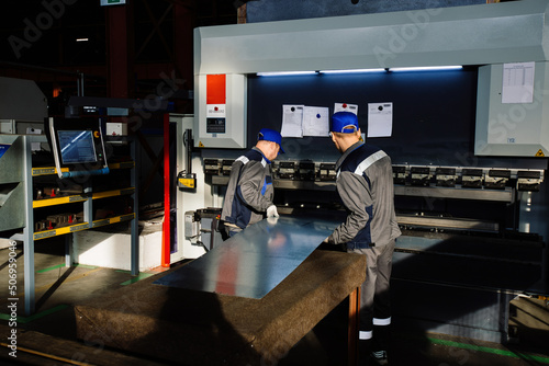 Technician operators working with with sheet metal on CNC hydraulic press brake