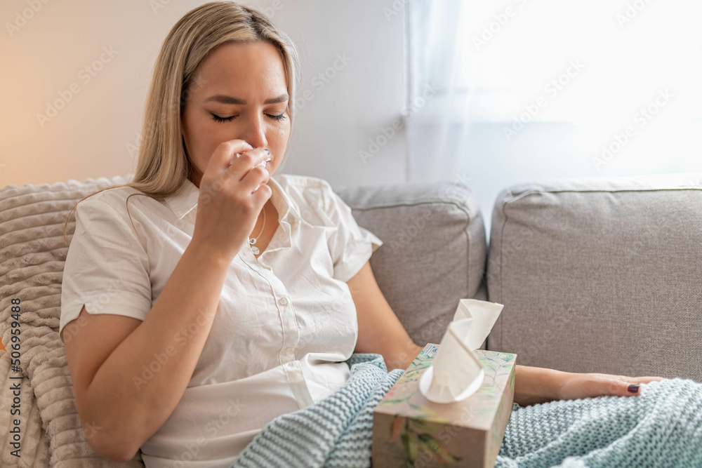 Sick woman sitting under the blanket. Sick woman with seasonal infections, flu, allergy lying in bed. Sick woman covered with a blanket lying in bed with high fever and a flu, resting and drinking tea Sick woman sitting under the blanket. Sick woman with seasonal infections, flu, allergy lying in bed. Sick woman covered with a blanket lying in bed with high fever and a flu, resting and drinking tea