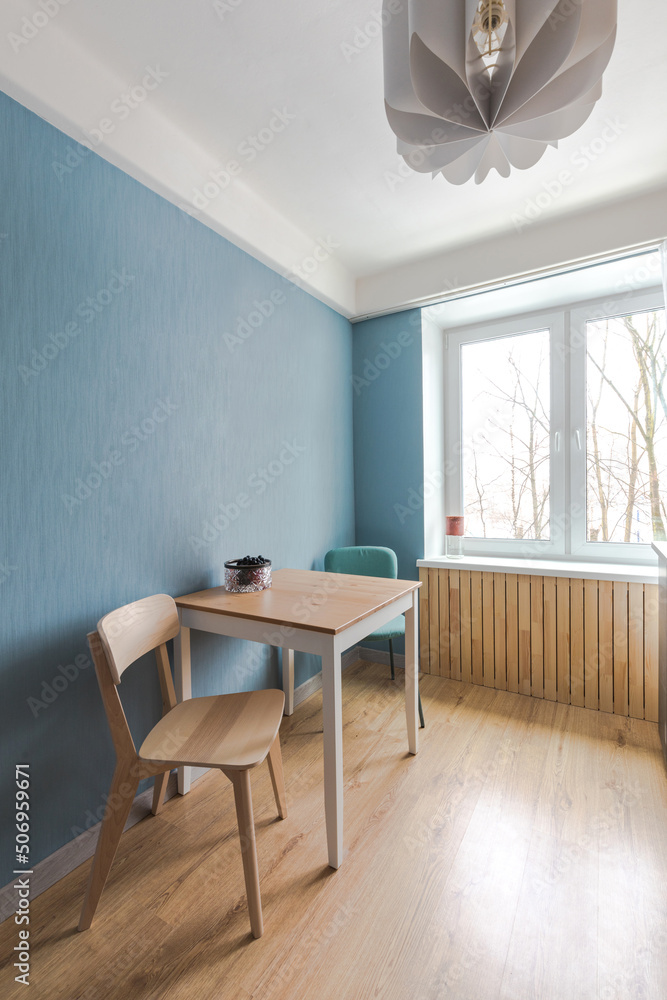 Fototapeta premium Minimalist kitchen with handleless fronts, no tall cabinets. Budget renovation in housing, area of ​​ten square meters