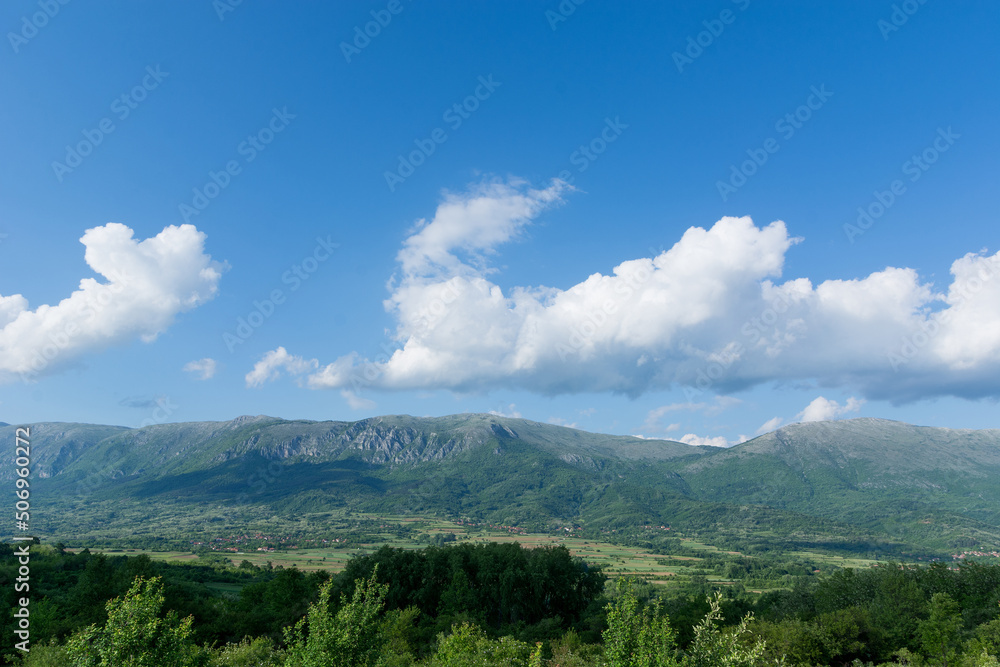 Panorama of mounts of the Suva Planina, a chain of mountains and hills in Serbia, with forests, hills and agricultural fields on a spring sunny day