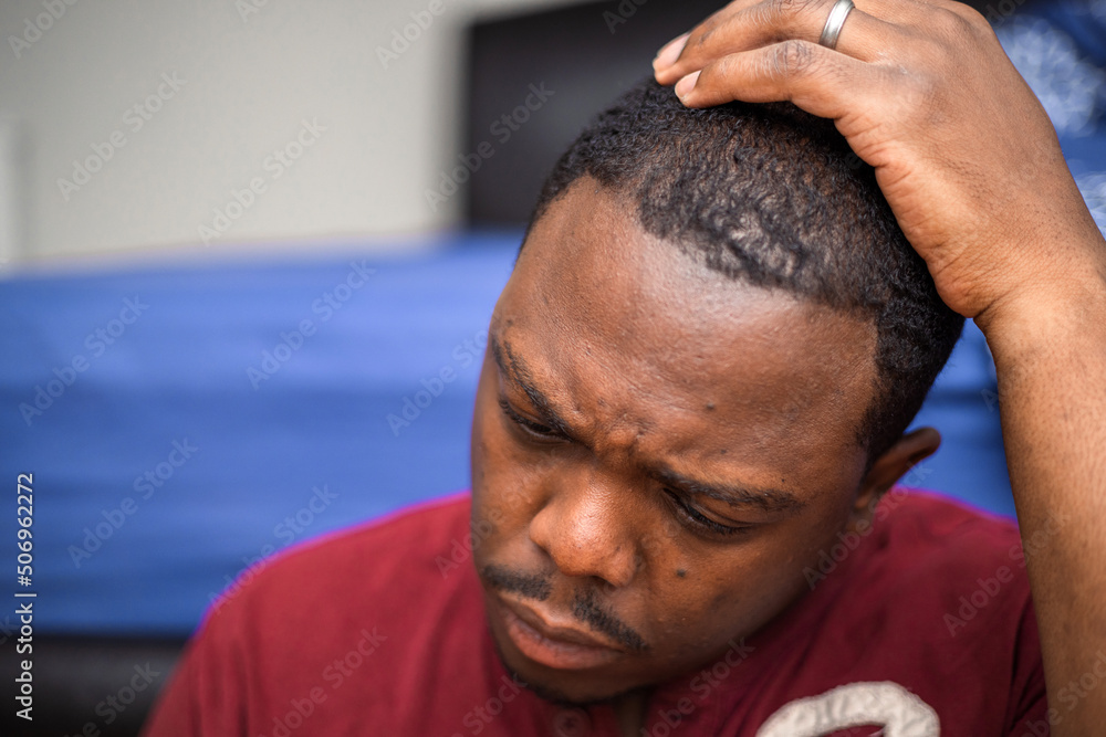 Fototapeta premium Depressed and anxious African American or black man sitting at home