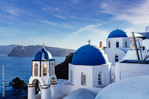 Santorini famous view. Blue domed churches on the Oia cliff with Aegean sea and Caldera in background.