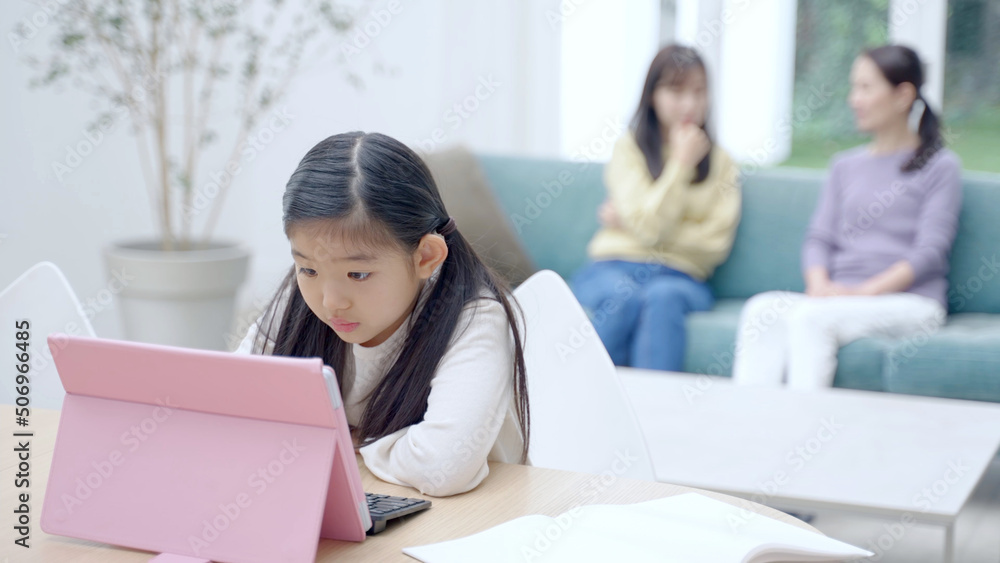 タブレットを使って学習をする女の子と見守る家族 タブレットを使って学習をする女の子と見守る家族