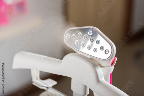 Close up of electric hand steam generator while it's hot on the ironing board place for clothes at house, Household & home equipment for housework, concept of linen care