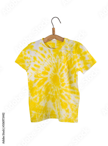 Bright yellow tie dye T-shirt on a wooden hanger isolated on a white background.