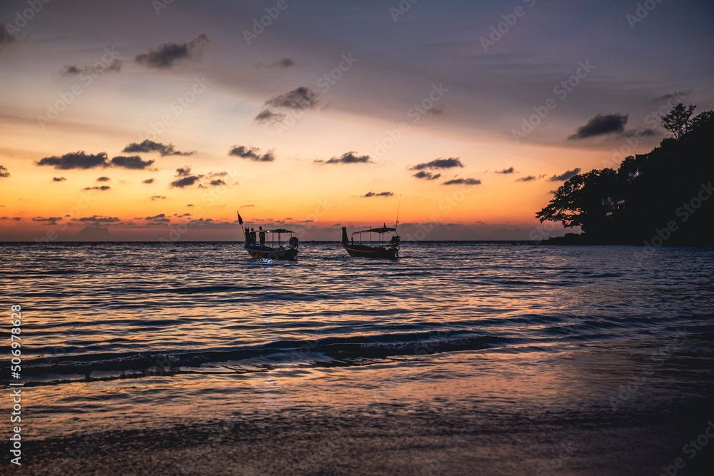 two fishing boats on the background of the sunset on the shore of Phuket Thailand
