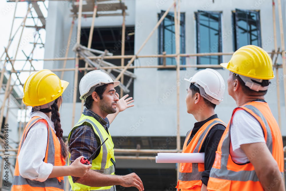 Multiethnic diverse group of engineers or business partners at construction site, working together on building's blueprint, architect industry or teamwork concept. Multiethnic diverse group of engineers or business partners at construction site, working together on building's blueprint, architect industry or teamwork concept.