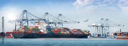 Panorama of Container cargo freight ship during discharging at industrial port move to container yard by trucks, handlers, cargo plane, logistic import export background and transport industry concept