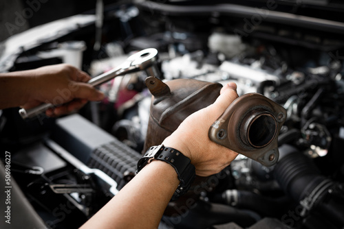 Close up old catalytic converter in hand Car service man and holding a wrench for remove part in engine room of car , service and maintenance concept in garage