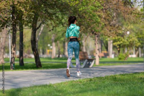 Full length photo of a woman running in park in early morning. Attractive looking woman keeping fit and healthy.