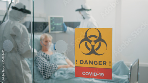 Close up of danger sign on glass of hospital ward for isolated area against coronavirus epidemic. Biohazard symbol for isolation in intensive care room at contagious zone. Outbreak of pandemic