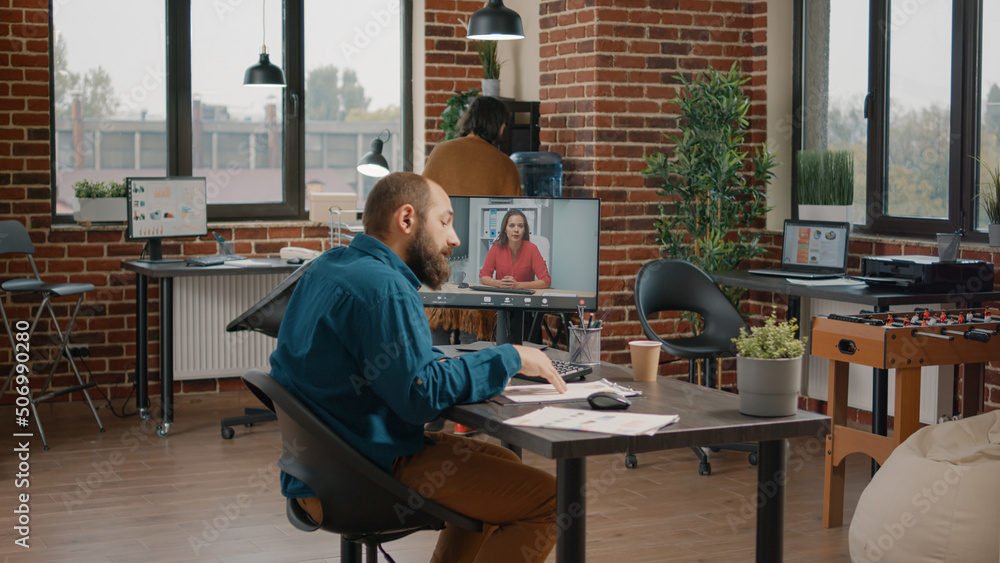 Business man doing video call meeting with woman on computer, talking about marketing strategy and analysis. Employee using online remote conference to talk to colleague on monitor.