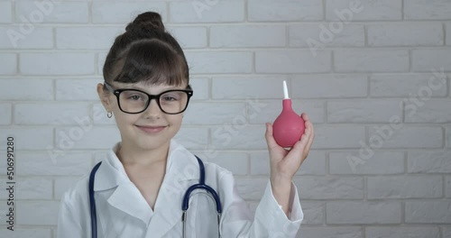 Child with enema. A smiling child play with an enema like a nurse in the room.