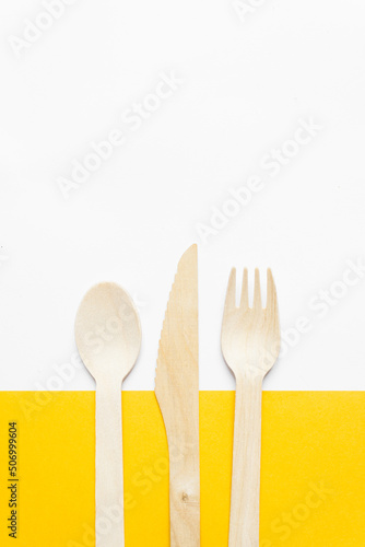 Slika na platnu Disposable tableware from natural materials - bamboo wooden fork, spoon and knife isolated on a yellow background