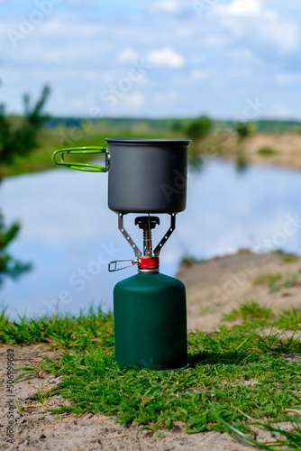Gas tourist burner with alluminium pot on background river 