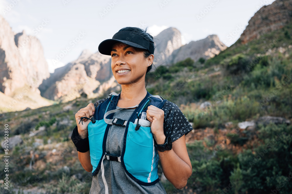 Portrait of a smiling woman in hiking attire looking away while standing in the valley Portrait of a smiling woman in hiking attire looking away while standing in the valley