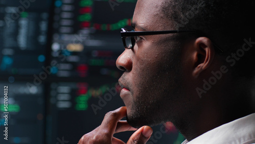 Fotografía Close up of pensive African-American programmer looking at computer monitors wit