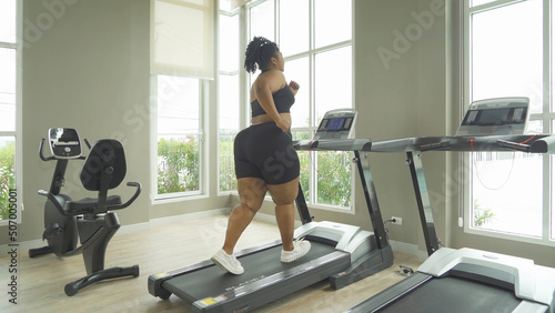 Fat black African american healthy woman, person, running or jogging on treadmill for diet, and training in gym or fitness center in sport and recreation concept. Lifestyle activity. Losing weight