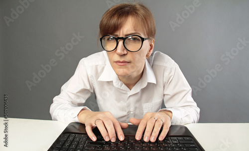 Businesswoman using laptop and looking at the camera isolated on studio grey background