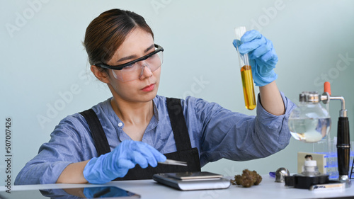 Scientist holding a test tube of cannabis oil. Herbal alternative medicine, cbd oil, pharmaceutical industry concept