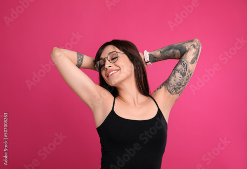 Woman with tattoos on arms against pink background