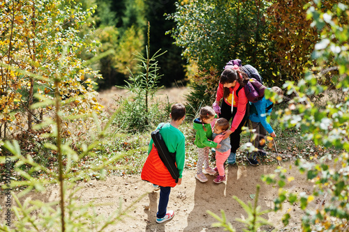 Mother with four kids in mountains. Family travel and hiking with childrens. Sisters is hug each other.