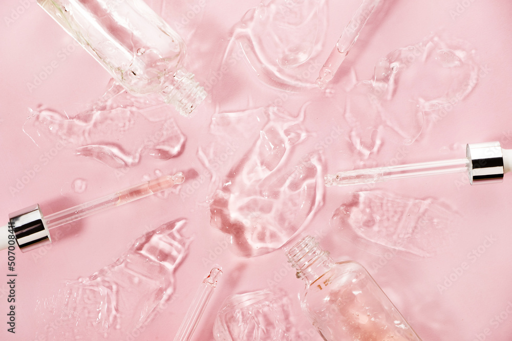 Close up of different pipette with pouring liquid essential oil on pastel pink background. Dropper glass with a falling drop of aromatherapy oil close-up. Close up of different pipette with pouring liquid essential oil on pastel pink background. Dropper glass with a falling drop of aromatherapy oil close-up.