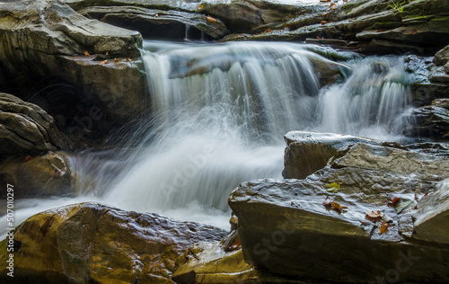 The fast flow of a mountain river among the stones. Long exposure. Motion blur. Selective focus.