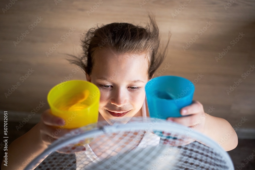 a little girl cools hot or warm water in the heat from the wind of a large fan in protest of the flag of ukraine