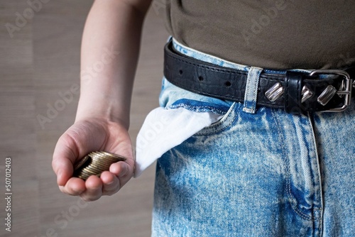 a handful of coins near the pocket of jeans pants as a sign or symbol of wealth or the last money from coins
