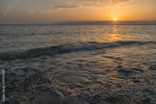 Tramonto sul mare con cielo nuvoloso e riflessi del sole sull acqua.