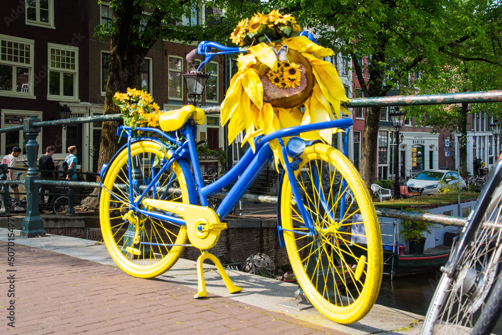 Amsterdam, Netherlands, May 2022. A flower-decorated bicycle against the railing of a bridge in Amsterdam.