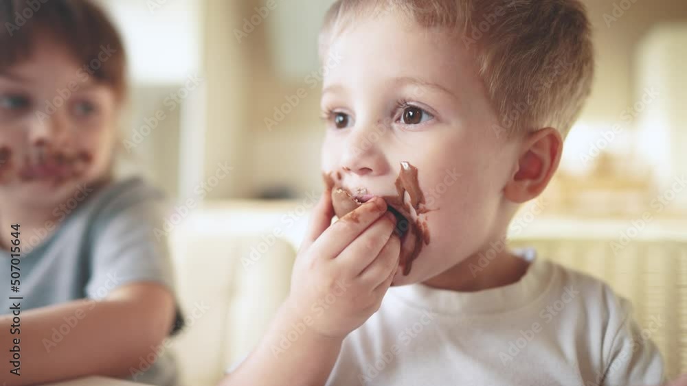 children eat chocolate. dirty little baby kids in the kitchen eating chocolate in the morning. happy lifestyle family eating sweets kid dream concept. baby dirty face eating chocolate cocoa