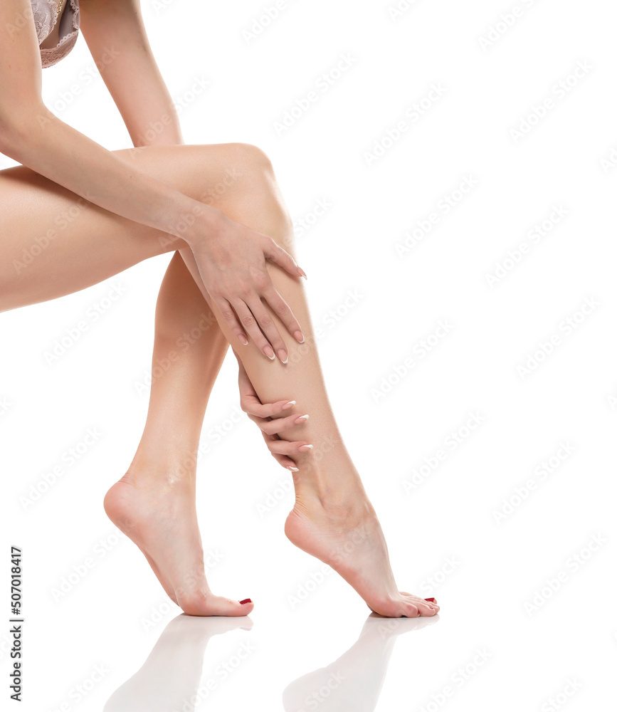 Young woman touching her smooth long legs, and putting on moisturizer after shaving her legs Young woman touching her smooth long legs, and putting on moisturizer after shaving her legs