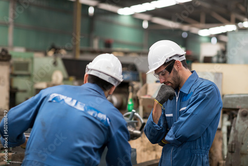 Two engineer male worker maintaining machine lathe metal at the industry factory. Group of Factory worker check or maintenance CNC machine in industry factory