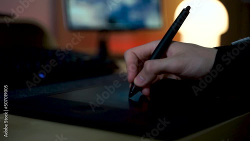 Close-up of hand drawing on a digital tablet with pen. Professional retoucher working on graphic tablet.