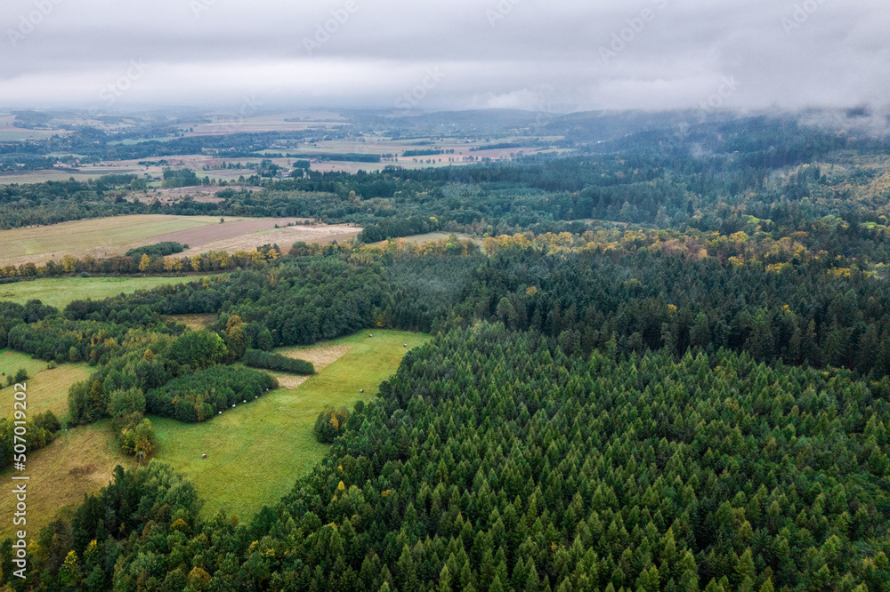 Aerial landscape of green hills and lush forest. Foggy and cloudy morning.