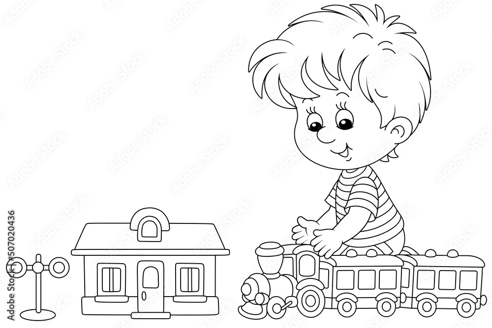 Happy little boy playing with a toy railway train and a station in his ...