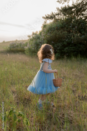 child walks in the park. little girl dressed in a blue dress. © Dmytrii