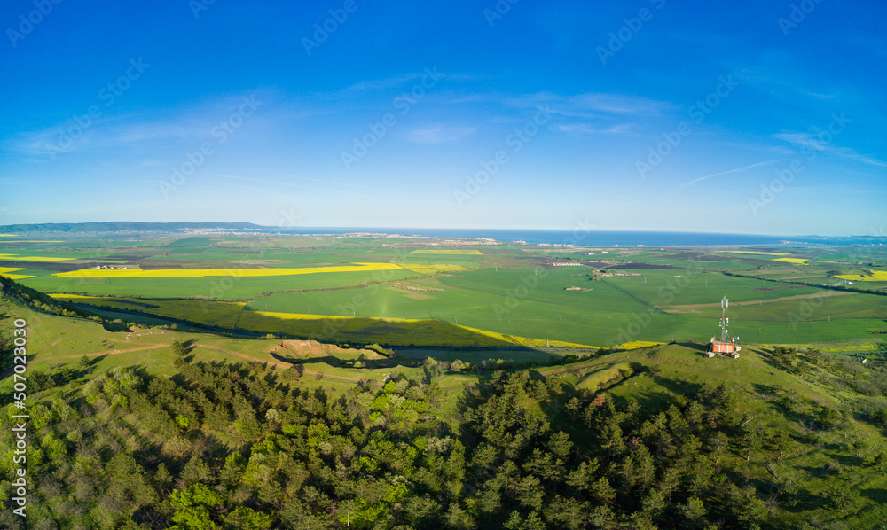 Panorama of the fields with a plant in a valley against the background of the village and the sky in Bulgaria