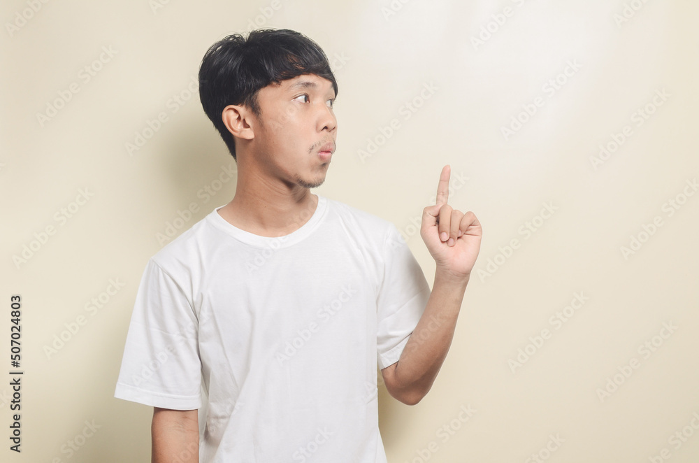 happy asian man wearing bright white t-shirt with gesture pointing to empty space on isolated background happy asian man wearing bright white t-shirt with gesture pointing to empty space on isolated background