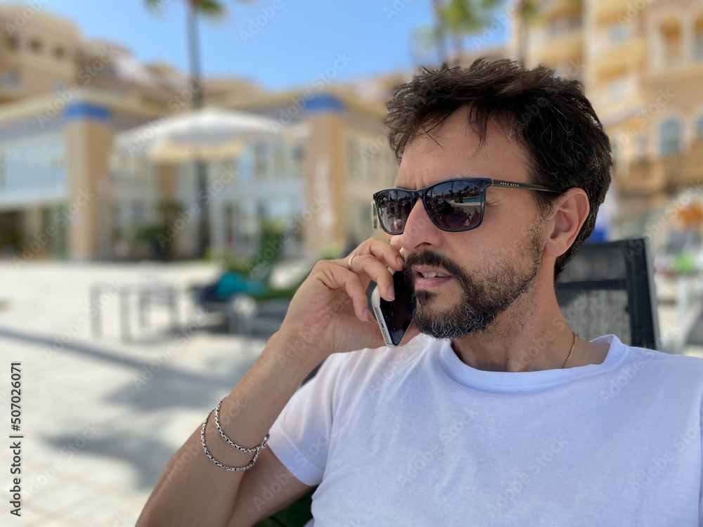 Young man talking on a cell phone at a hotel pool Young man talking on a cell phone at a hotel pool