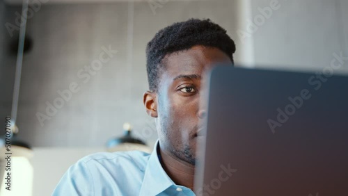 Portrait of young african american man in living room using laptop close-up