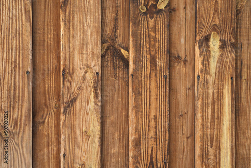 The texture of a wooden old vintage fence made of planks. Natural color of faded wood with old nails