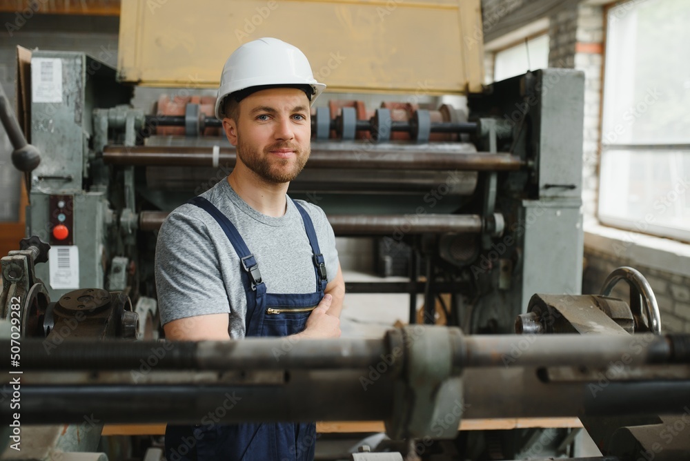 Smiling and happy employee. Industrial worker indoors in factory. Young technician with white hard hat. Smiling and happy employee. Industrial worker indoors in factory. Young technician with white hard hat.