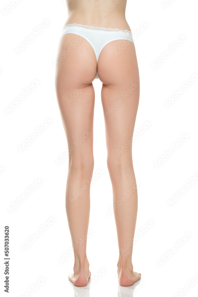 Rear view of female barefoot legs in white bikini panties on a white studio  background Stock Photo