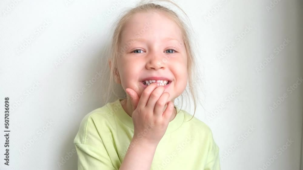 Portrait of a girl pulling out her baby tooth. Change of teeth. Loss of a baby tooth. The child's front tooth is loose. Portrait of a girl pulling out her baby tooth. Change of teeth. Loss of a baby tooth. The child's front tooth is loose.